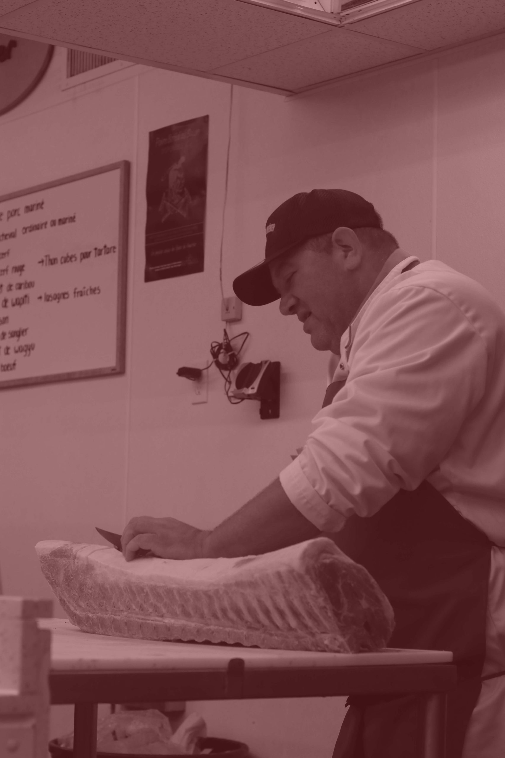 Homme qui coupe de la viande dans la boucherie